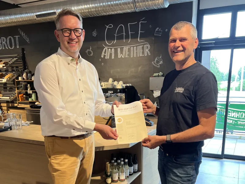 Landrat Ingo Brohl gratuliert "Café am Weiher"-Besitzer Klaus Bird zur Bio-Zertifizierung in Gold.